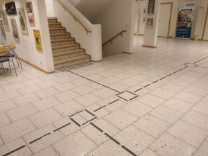 Ledelinjer i blankt stål med sort innlegg, med retningsendringsfelt og oppmerksomhetsfelt. Fra Modum kulturhus